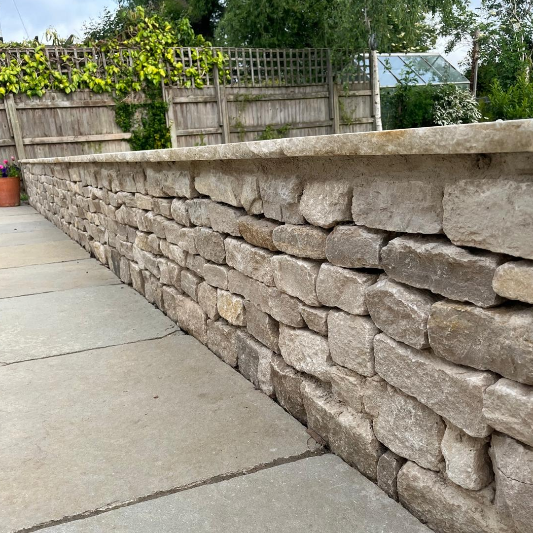 Stone wall with a patio slabs in a garden in Henley-On-Thames.