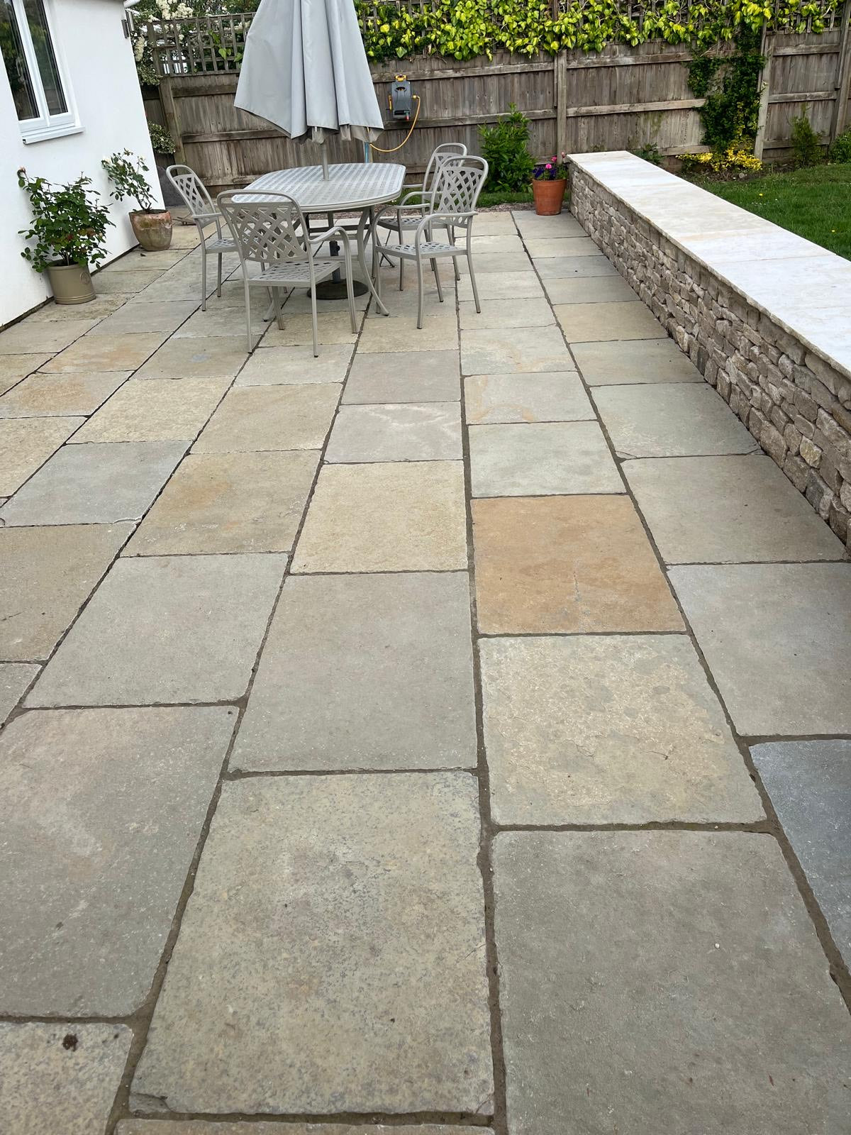 Paved patio area with outdoor furniture and a dry stone wall.
