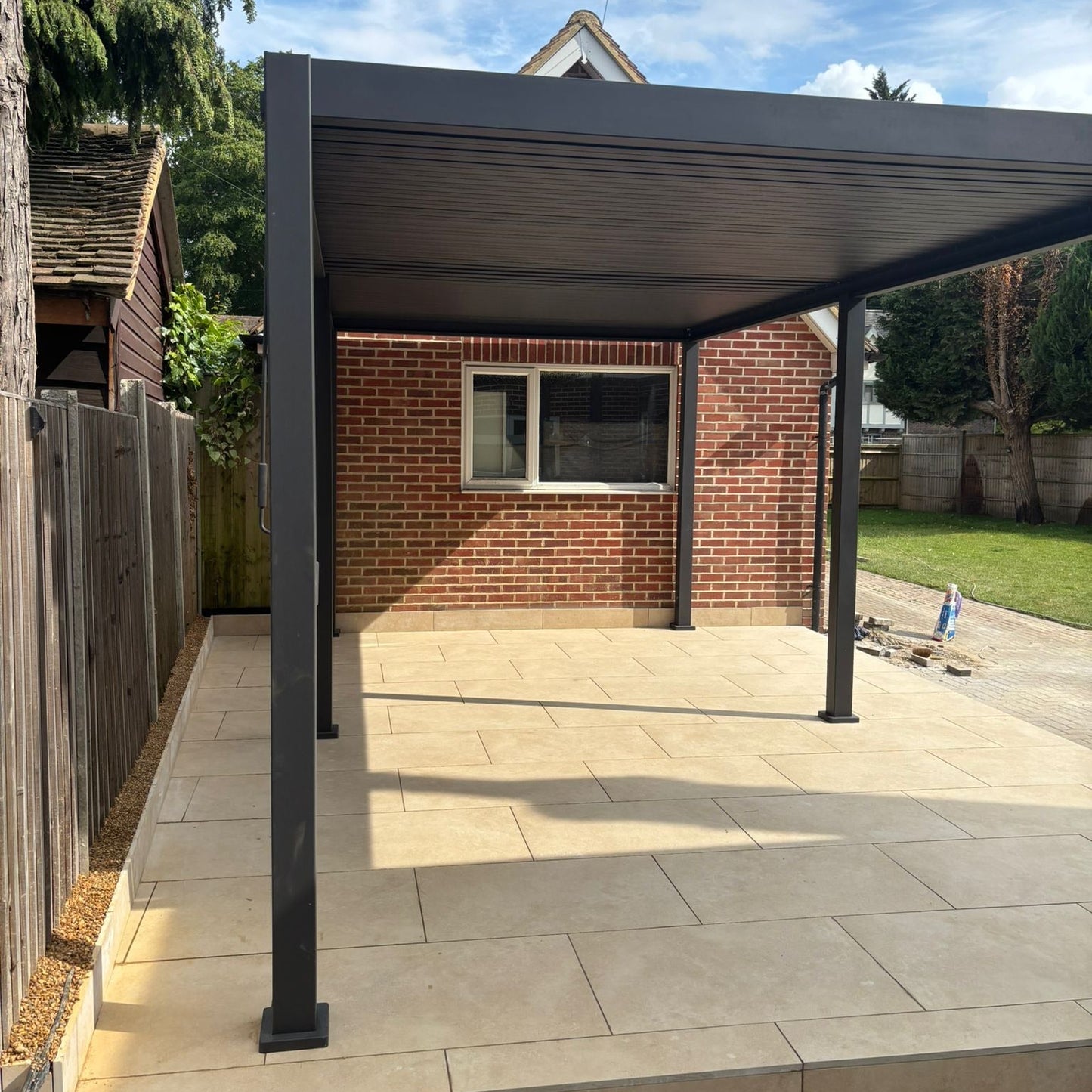 Patio cover attached to a brick house with a clear blue sky