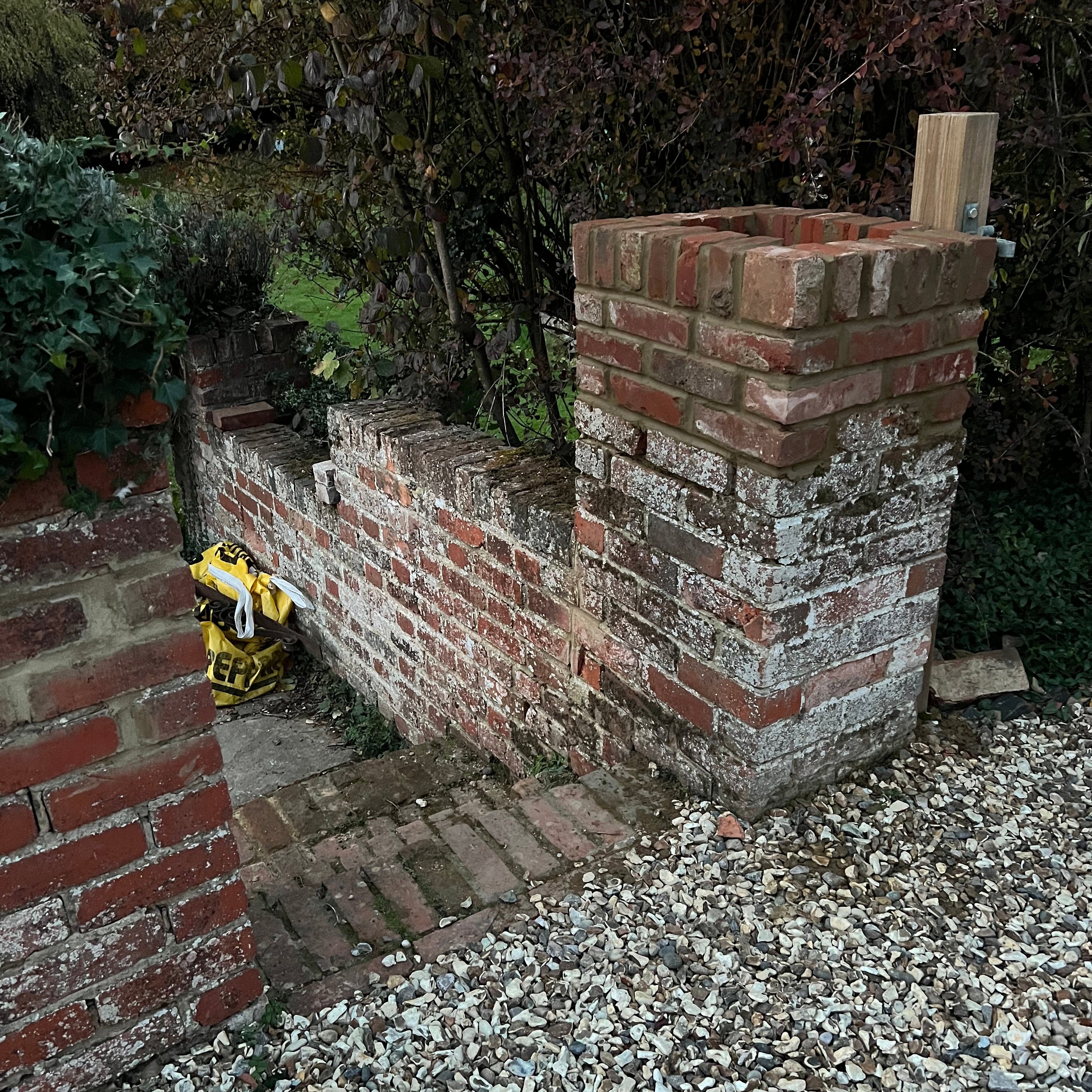 Red brick wall built on property in Binfield Heath, surrounded by greenery.