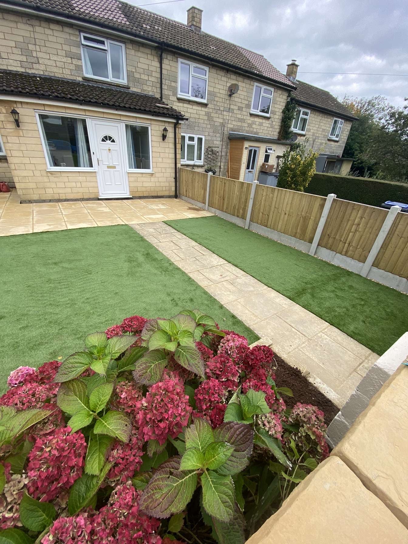 Artificial turf, timber fencing, patio slabs and soft landscaping in garden in Shiplake. 