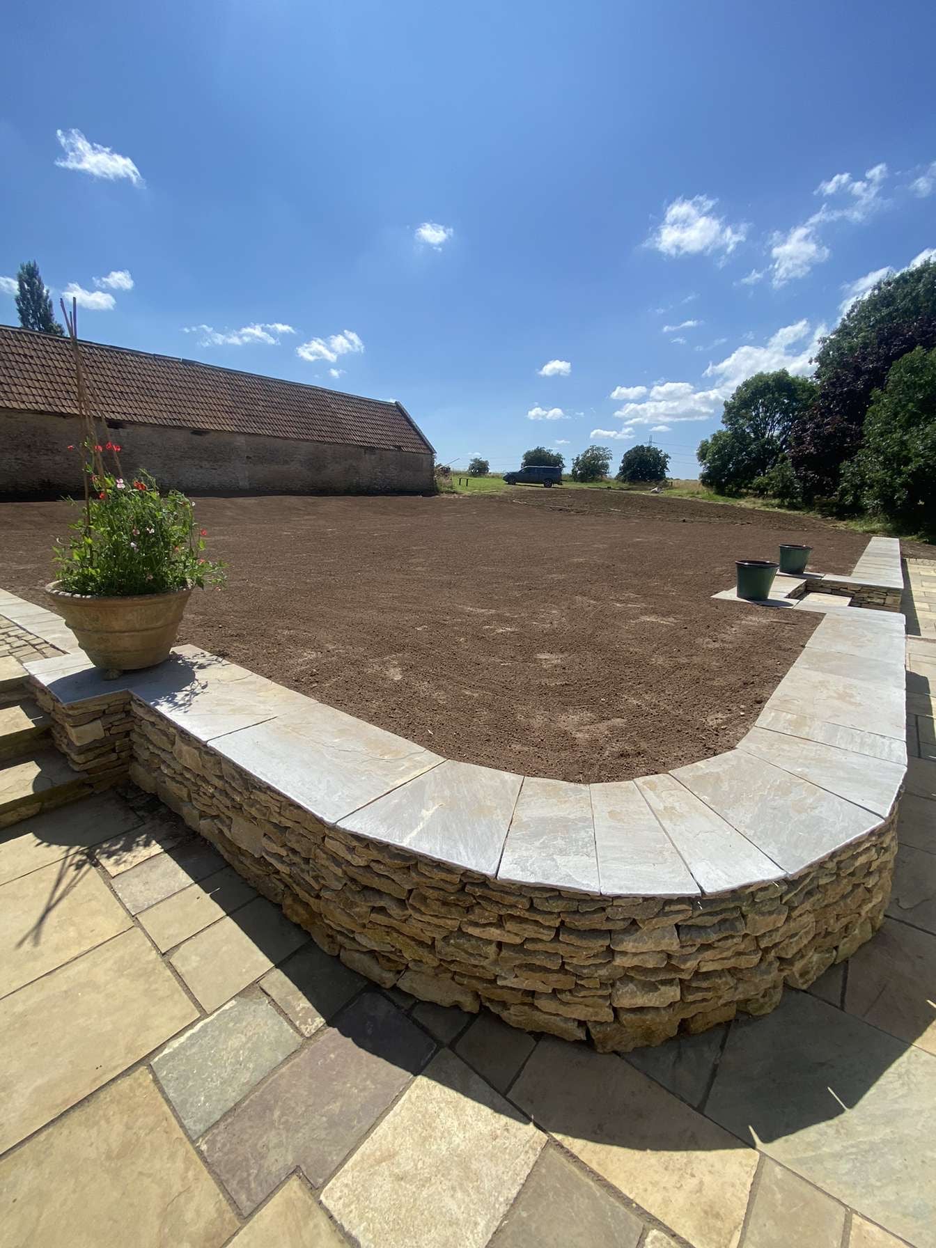Curved dry stone wall in Oxfordshire topped with Indian Sandstone paving slabs