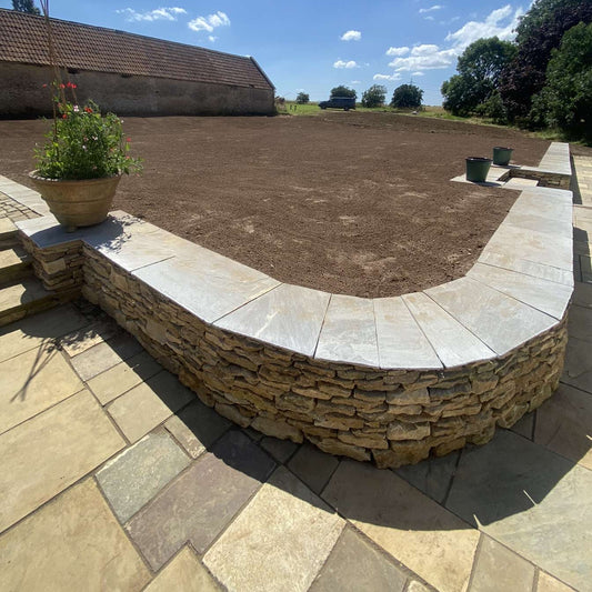 Curved dry stone wall in Oxfordshire topped with Indian Sandstone paving slabs