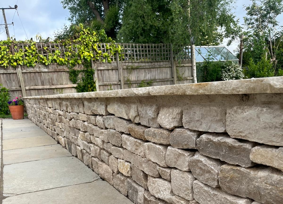 Stone wall with a patio slabs in a garden in Henley-On-Thames.