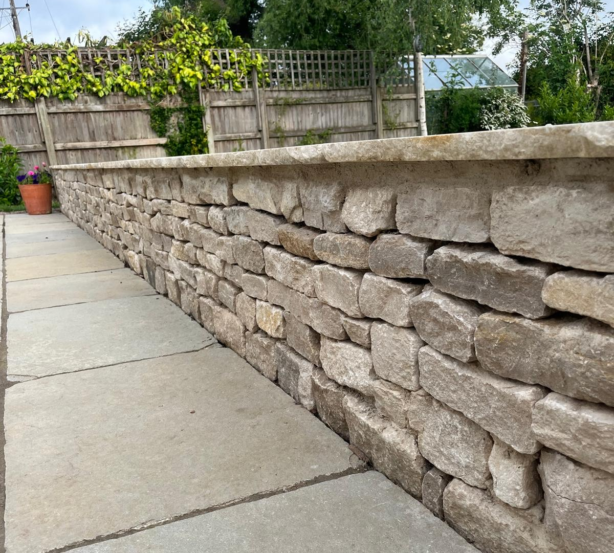 Stone wall with a patio slabs in a garden in Henley-On-Thames.