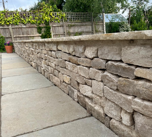 Stone wall with a patio slabs in a garden in Henley-On-Thames.