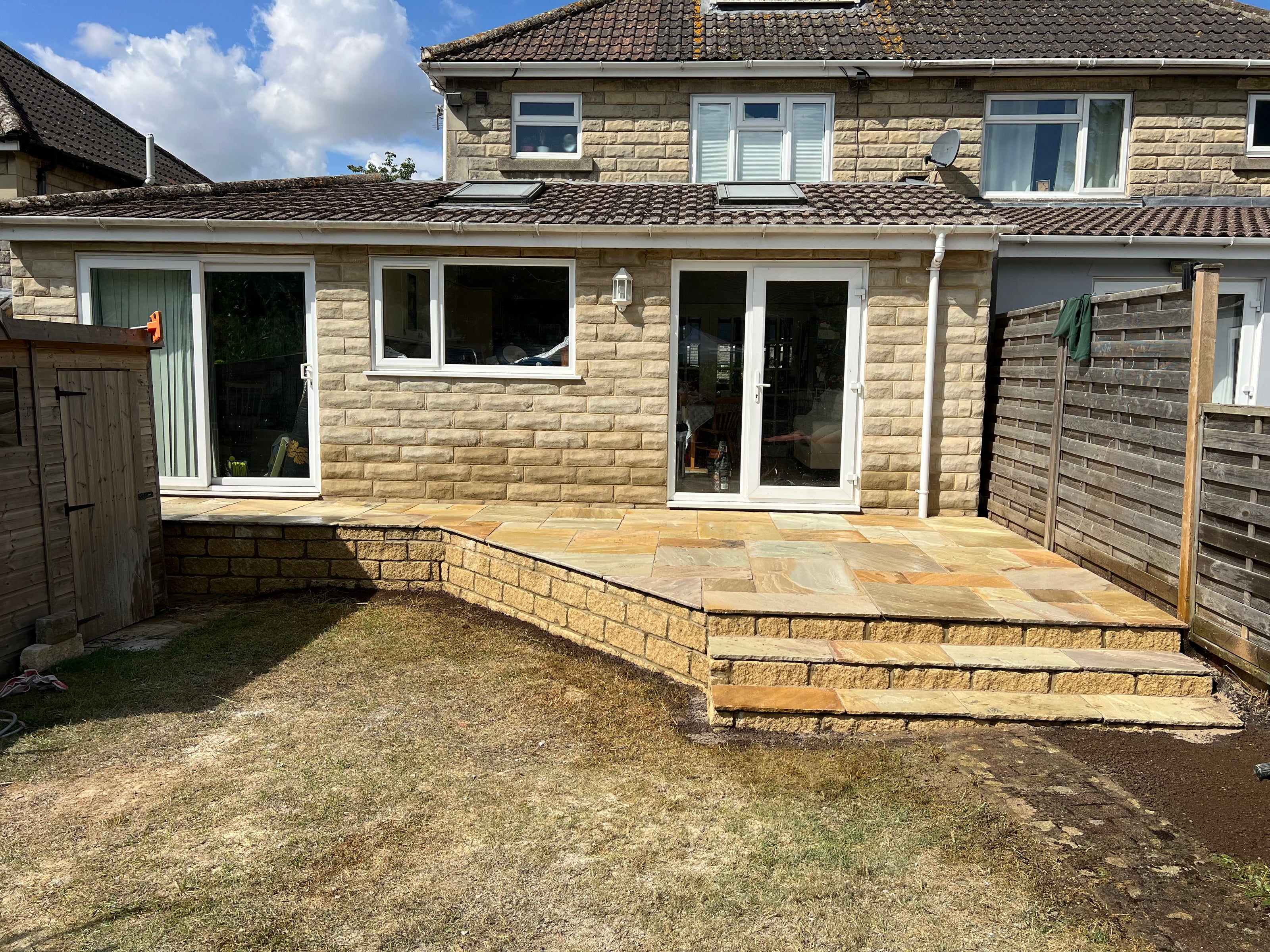 Back garden of house in Henley on Thames with retaining wall and patio.