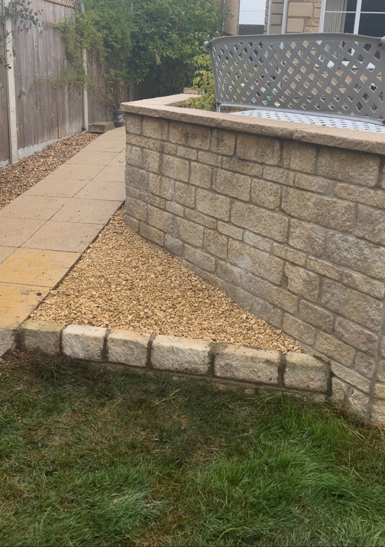 Garden area in Henley-on-Thames with a stone wall, slabbed pathway, and garden furniture.